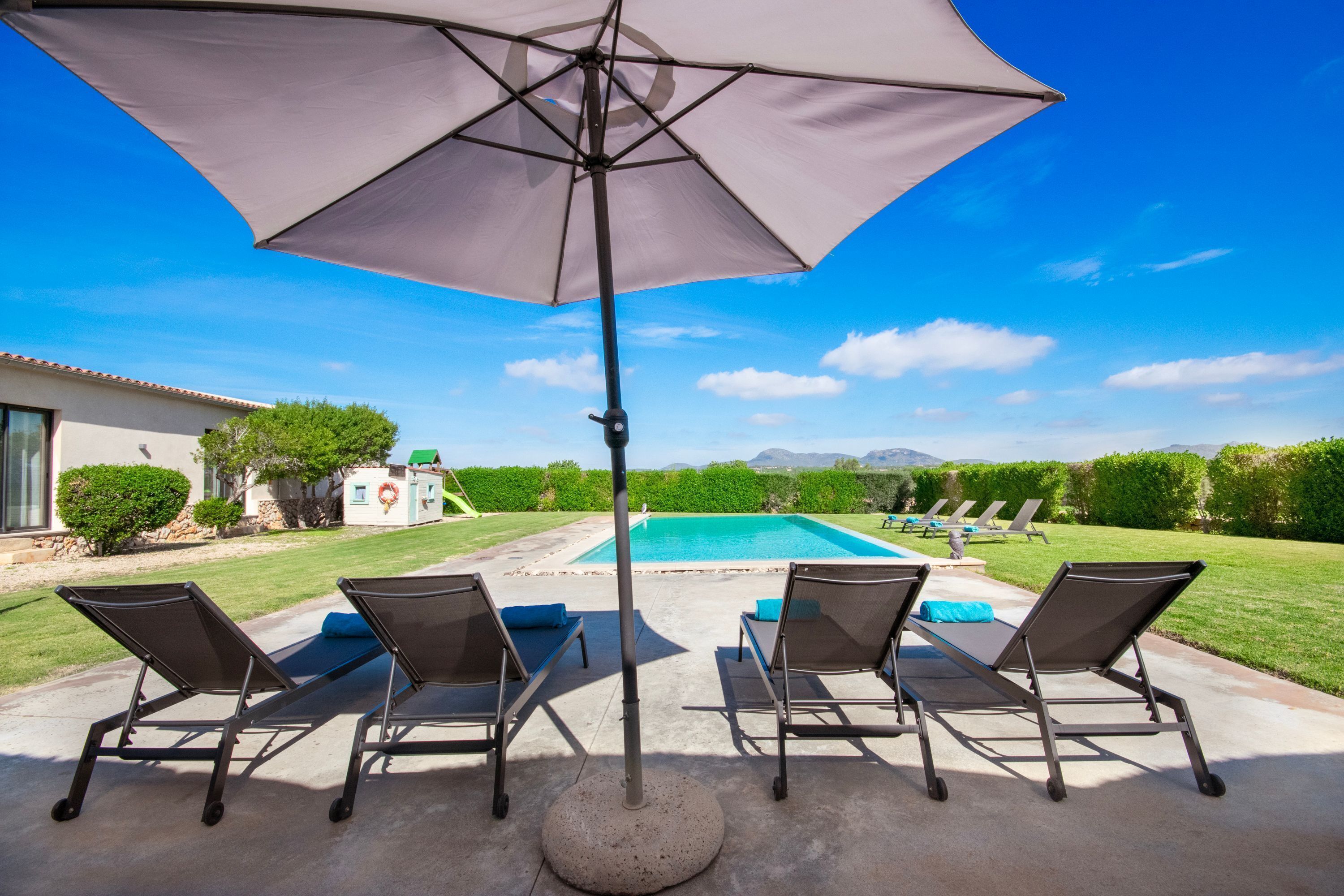 A poolside area with lounge chairs and a large umbrella.