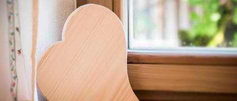 Un objet en bois en forme de cœur, appuyé contre le rebord d’une fenêtre.