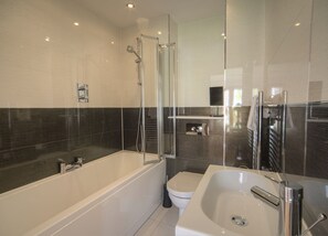 Ein modernes Badezimmer mit einer Dusche in Glasabtrennung, einer freistehenden Badewanne und einem separaten Waschbeckenbereich.