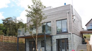 A modern two-story house with a stone facade, large windows, and a balcony. - Beautifully decorated "Sea Shack", with large sun roof terrace and large private hot tub. (Looe)