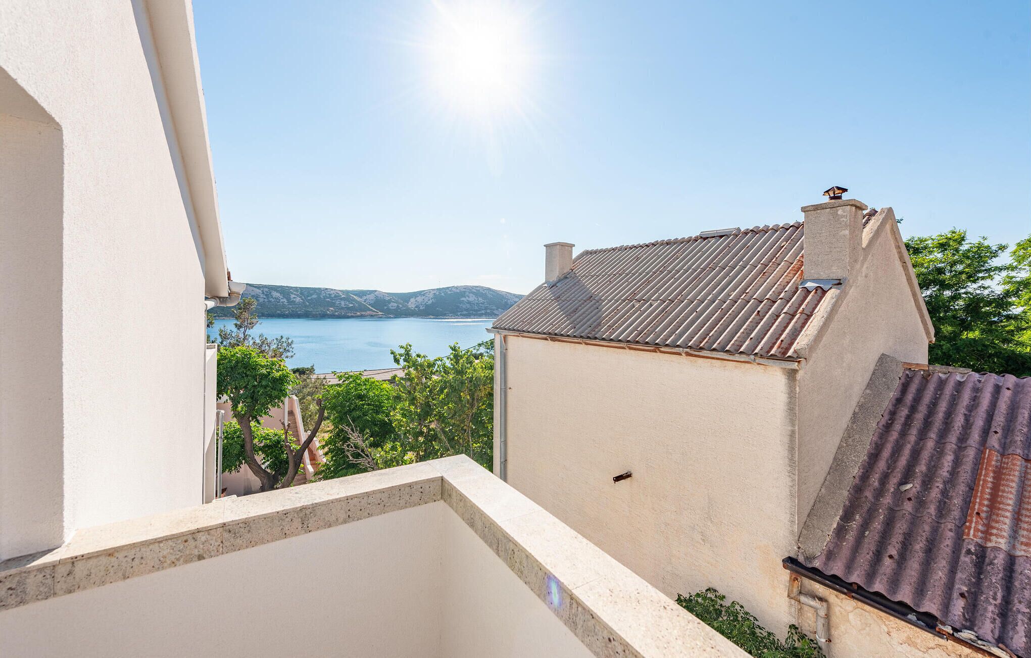 Un balcon avec vue sur un lac et des collines lointaines.