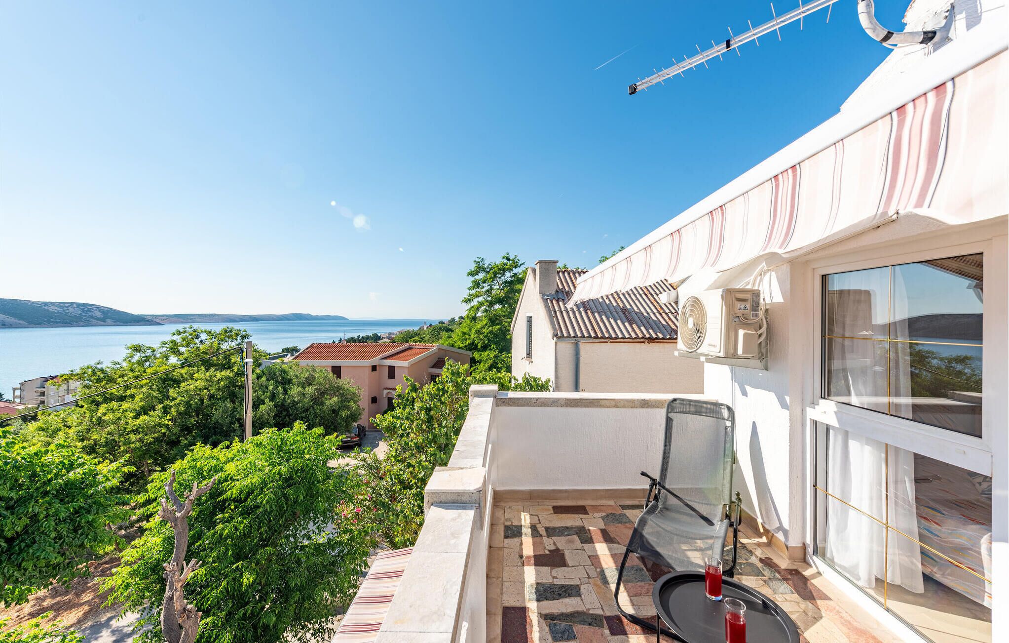 Un balcone con vista sul mare, pavimento piastrellato e una sedia.