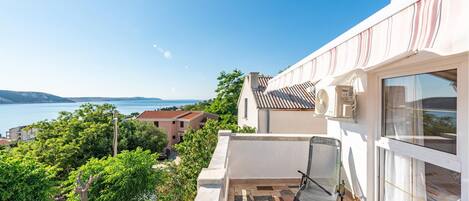 Un balcone con vista sul mare, pavimento piastrellato e una sedia.