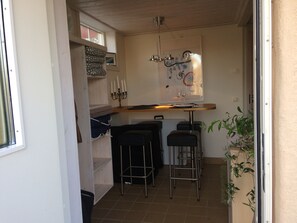 Een kleine keuken met een bar, een hanglamp en een plant in pot.