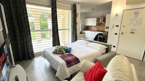 Ein Hotelzimmer mit Bett, Sofa, Fernseher, Küchenzeile und einer Tür mit einem Schild.