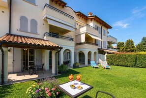 A multi-story building with balconies, outdoor seating, and a well-maintained lawn.