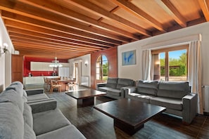Ein modernes Wohnzimmer mit einer Couch, zwei Sesseln, einem Couchtisch und einem Essbereich mit Stühlen und einem Tisch.