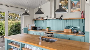 Une cuisine moderne avec des meubles de couleur turquoise, un plan de travail en bois et des luminaires suspendus.