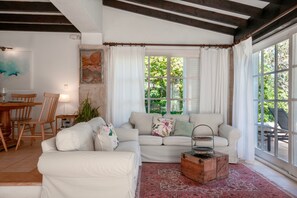 Ein Wohnzimmer mit einem weißen Sofa, einem Holztisch und einem Essbereich mit Holzsesseln und einem Tisch.