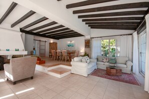 Un espacio habitable amplio con techo alto, un comedor con muebles de madera y una zona de estar acogedora con un sofá y sillones.