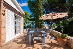 An outdoor patio with a table, chairs, and a large umbrella. - 44327 Villa Cala Padri - 44327 Villa Cala Padri (Provensals)