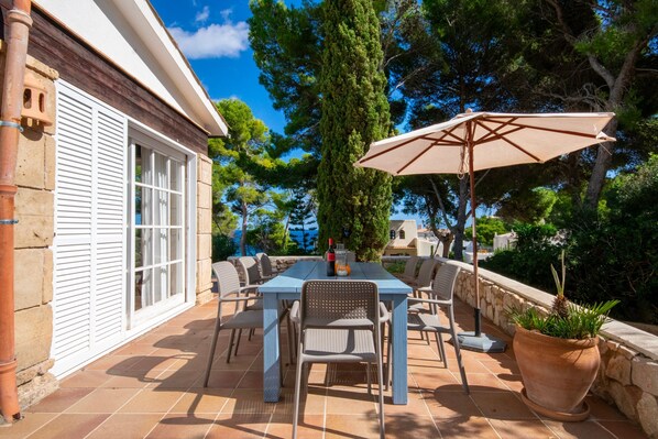An outdoor patio with a table, chairs, and a large umbrella.