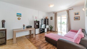 Ett kompakt bostadsutrymme med en säng, ett skrivbord, en tv och en bokhylla.