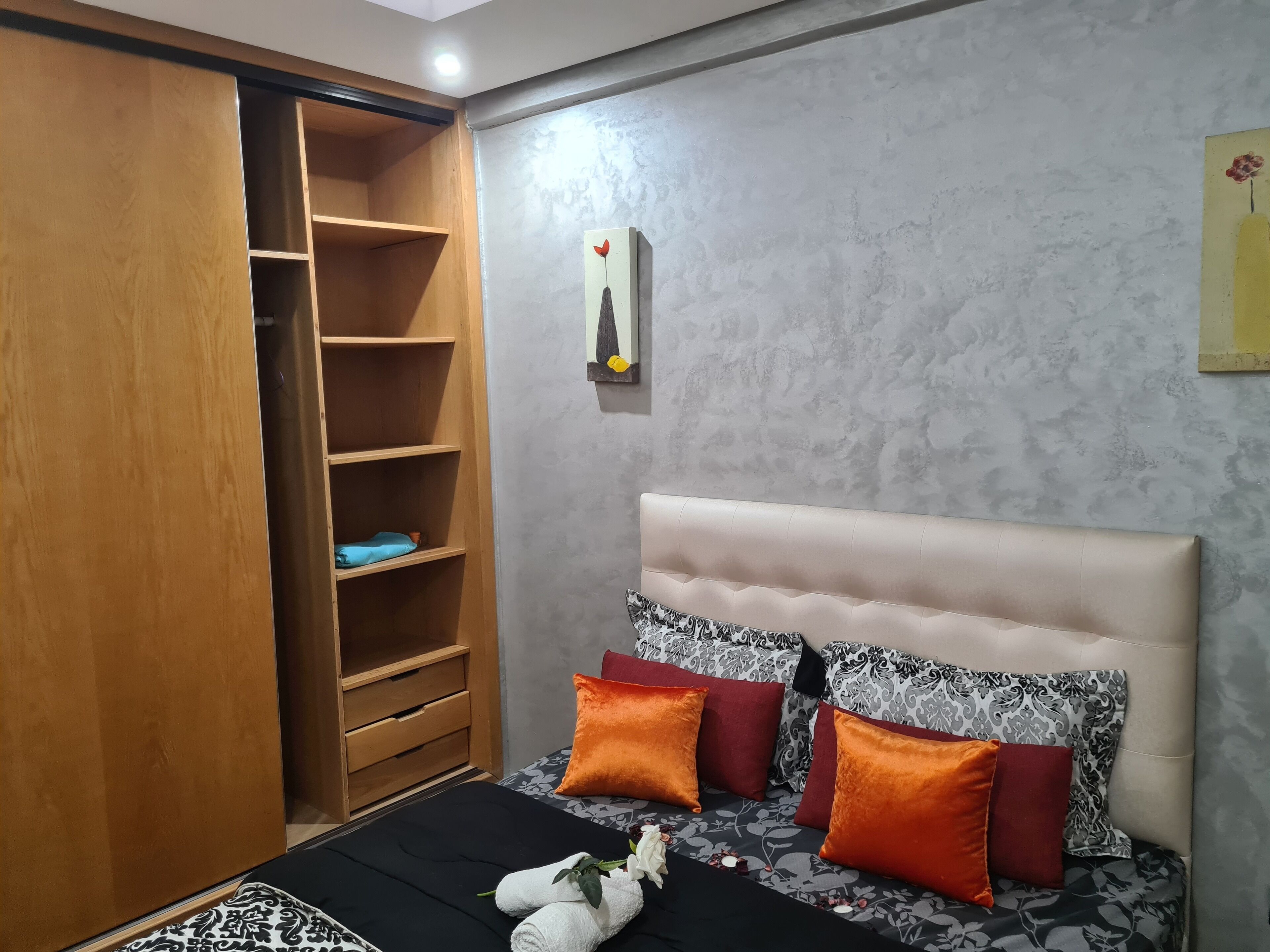 A bedroom with a bed, a wardrobe, and a wall-mounted artwork.