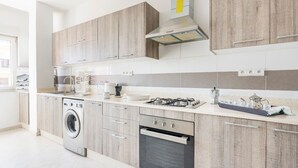 A modern kitchen with wooden cabinets, a built-in washing machine, an oven, and a gas stove. - Appartement 26 ensoleillé à 5 min de la plage El Jadida (El Jadida)