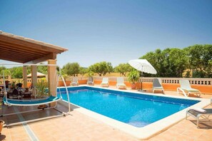 A swimming pool with lounge chairs and a covered seating area.