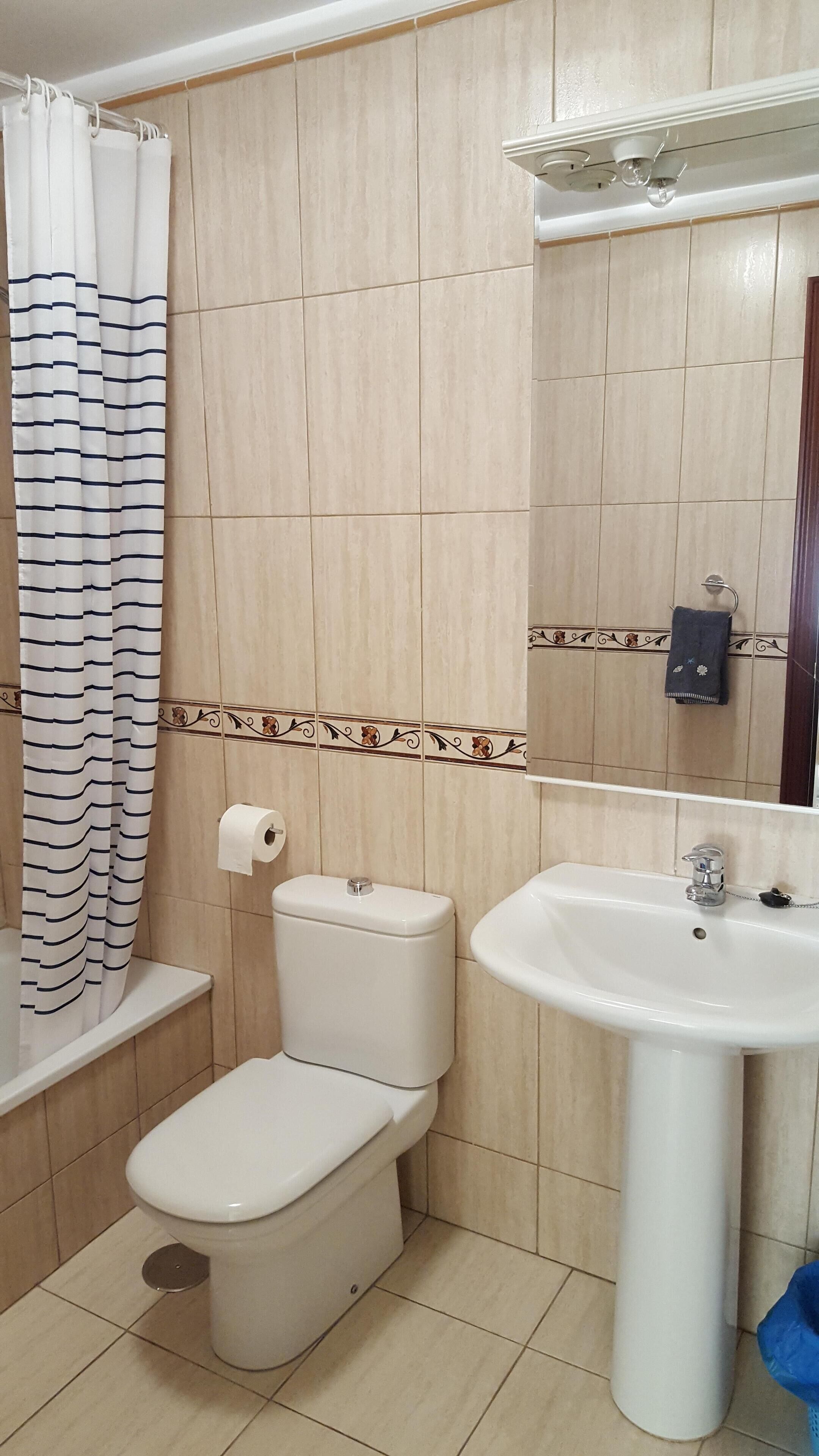 A bathroom with a toilet, sink, and shower curtain.