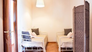 Ein Zimmer mit zwei Betten, einer Hängelampe und einer Holzwand.