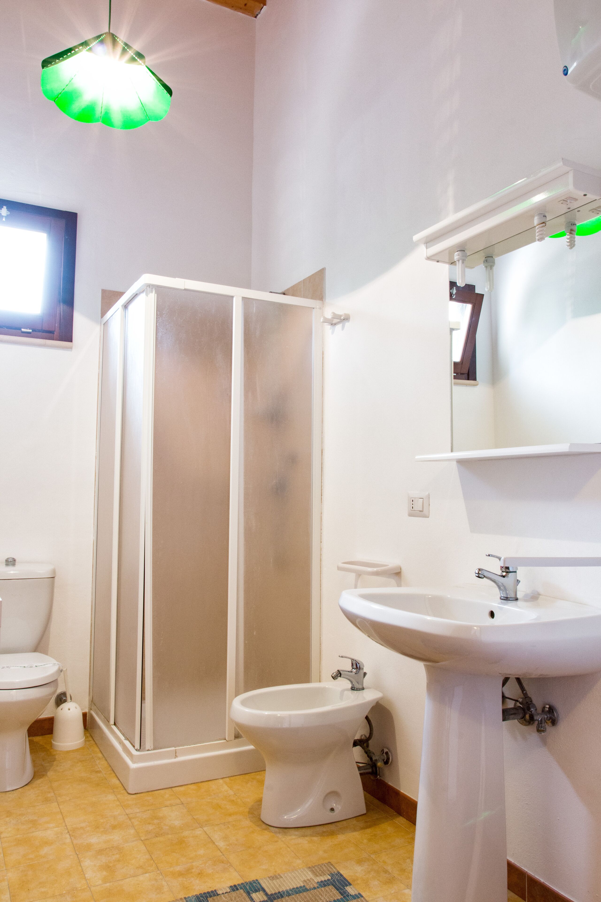 Et badeværelse med toilet, bidet, brusekabine og håndvask.