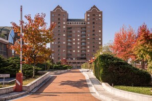 Um edifício de vários andares com fachada simétrica, um caminho pavimentado e folhagem de outono.