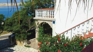 A white building with a balcony and an archway leading to a courtyard. - Beautiful apartment in Kustici with WiFi (Kustici)