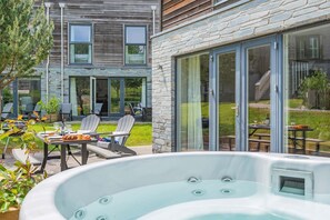 Eine moderne Außenpatio mit Whirlpool, Essbereich und Steinmauern.