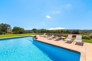 A swimming pool with lounge chairs and a view of the landscape.