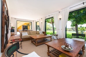 A spacious living area with a sofa, coffee table, and dining table. There is a television and a window with curtains. - Es Sestador (Porto Cristo) - 784526 Es Sestador (Manacor)