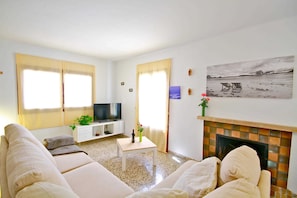 A living room with a sofa, a television, a small table, and a fireplace.