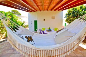 A hammock bed with a table and chairs in the background.