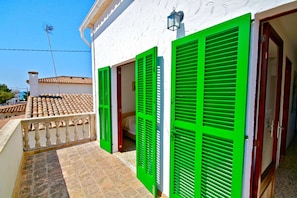 Un bâtiment avec des volets verts, un toit en tuiles et un balcon doté d’une balustrade.