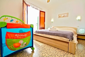 Un dormitorio con una cama, una cuna con juguetes, una puerta y un reloj de pared.