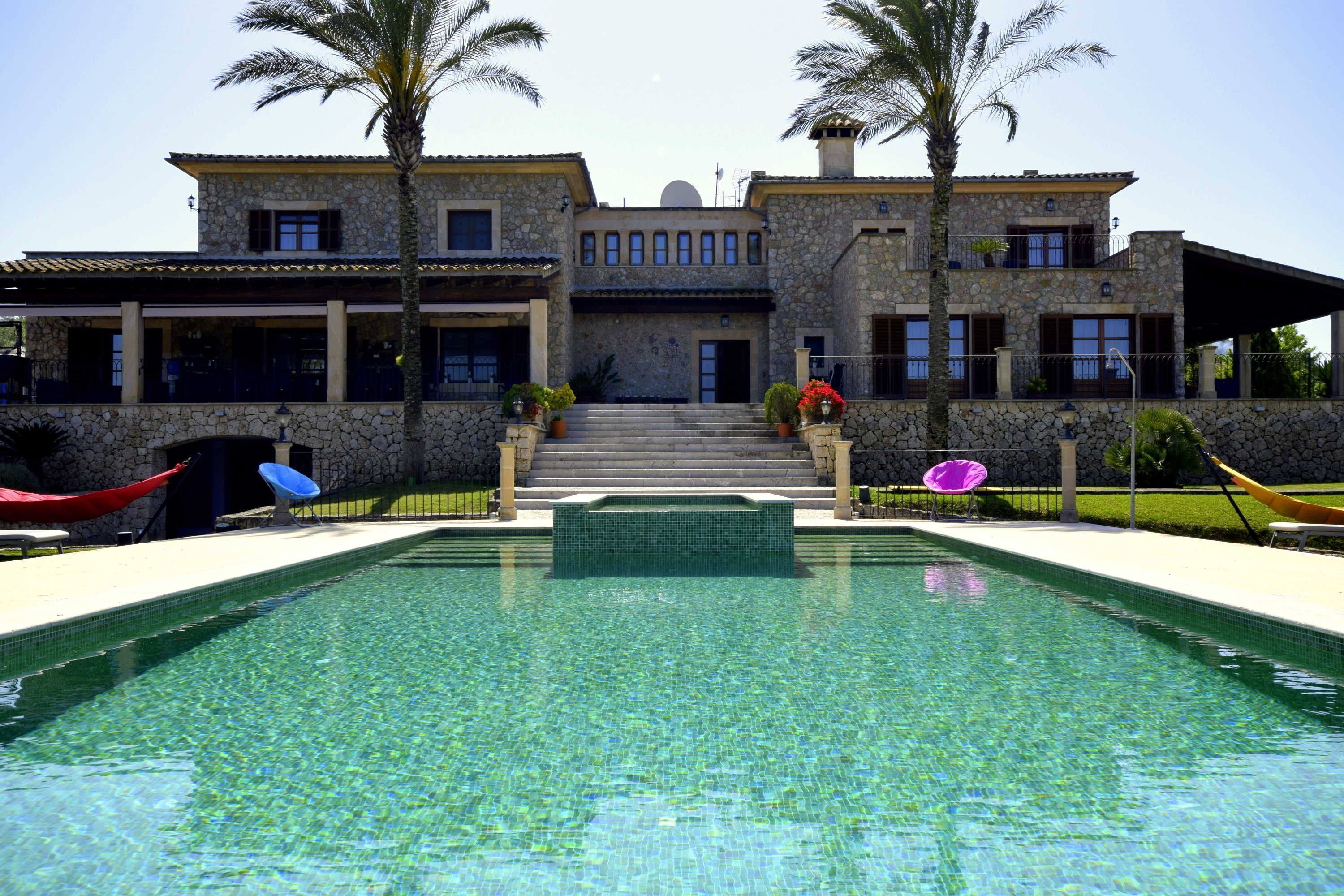Un grand bâtiment en pierre avec une piscine devant.