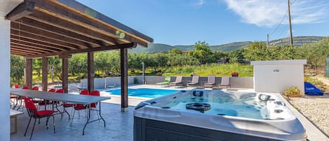 Un espacio al aire libre cubierto con un jacuzzi, una piscina y zonas de estar.
