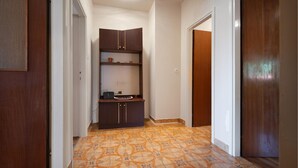 Un corridoio con pavimento piastrellato, un armadietto in legno e una porta.