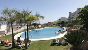 Ein Swimmingpool, umgeben von Palmen und Liegestühlen.
