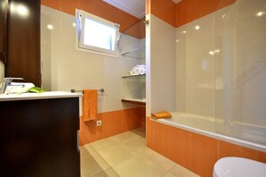 Een badkamer met een bad, toilet en wastafel.