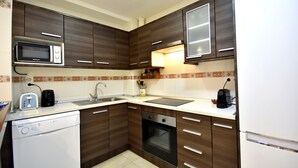 Una cocina moderna con armarios de madera oscura, microondas integrado, lavavajillas y estufa.