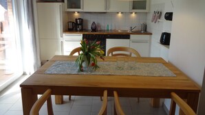 A modern kitchen with white cabinets, a wooden dining table, and a large pendant light.