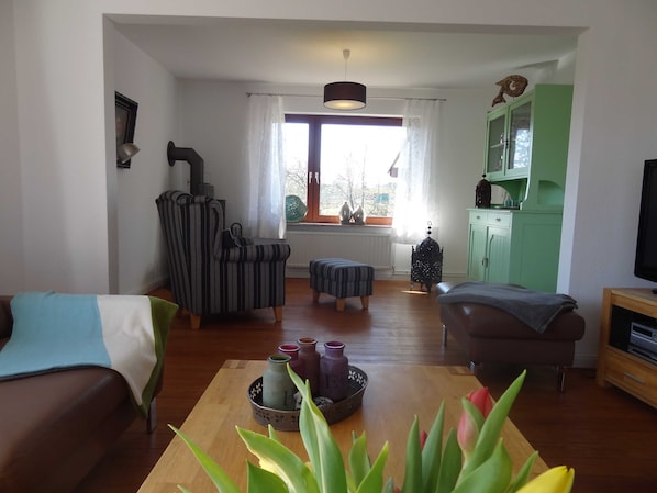A living room with a sofa, armchair, ottoman, and a coffee table with decorative items.