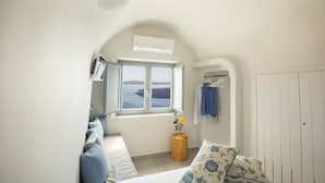 A bedroom with a view of the sea, a wooden stool with a flower, and a white wardrobe. - "Ethereum Luxury Cave" private jacuzzi villa in Imerovigli  (Santorini)