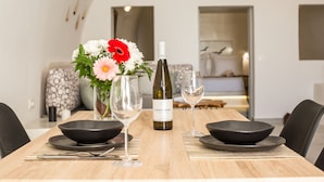 A dining table set with a bottle of wine, two bowls, and a vase with flowers. - "Ethereum Luxury Cave" private jacuzzi villa in Imerovigli  (Santorini)