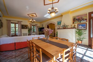 A dining area with a wooden table and chairs, a vase with flowers, and a chandelier.