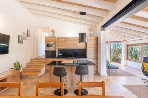 Eine moderne Küche mit einer zentralen Kochinsel, Barhocker und einem Essbereich mit Holztisch und Stühlen.
