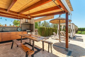 An outdoor kitchen area with a wooden table, a bench, and a grill. - 785879 Ses cases - 785879 Ses Cases (Manacor)
