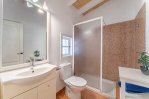A bathroom with a white sink, toilet, and shower area.