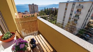 Un balcon avec vue sur la mer, une plante en pot et un banc en bois.