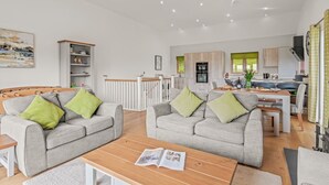 A modern living room with two grey sofas, a wooden coffee table, and a bookshelf.