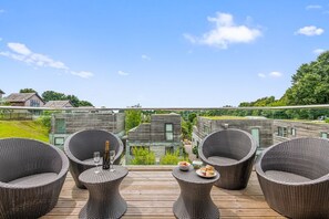 Een terras met rieten meubilair, een fles champagne en een schaal fruit.