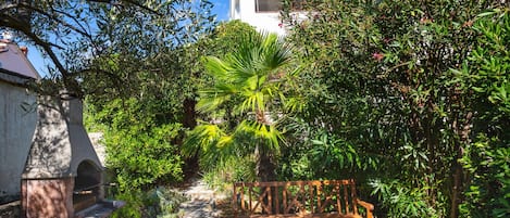 Un jardin avec un banc en bois, des marches en pierre et différentes sortes de plantes.